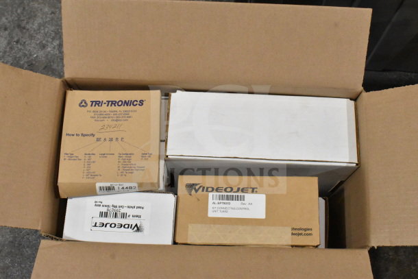 Two boxes containing a wash station kit, 25-way I/O breakout cable, and fiber optic light guide. Tri-Tronics and Videojet labels visible.