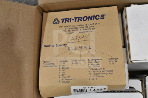 Boxes containing a Tri-Tronics fiber optic light guide, wash station kit, I/O breakout cable; labeled with specifications.