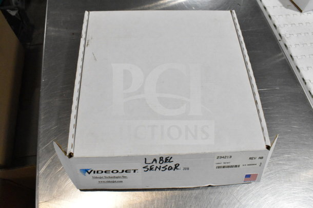 VideoJet Label Sensor box, item 234213, Rev AB, with USA flag, showcasing technology components for auction.