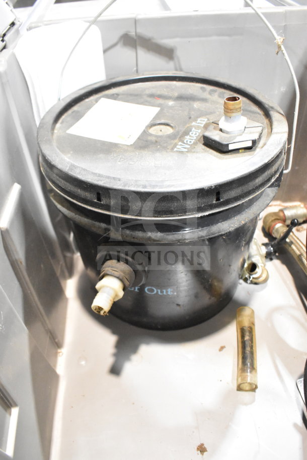 Bin containing water buckets and a water filter with visible in/out markings and fittings; used condition.