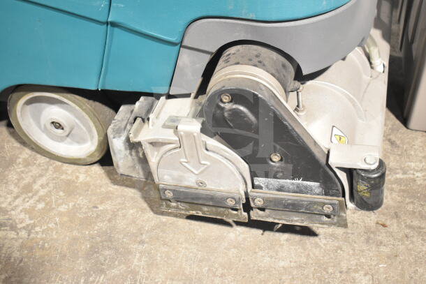 Tennant T5 Floor Cleaning Machine, visible brush mechanism, and wheels; used condition, durable build.