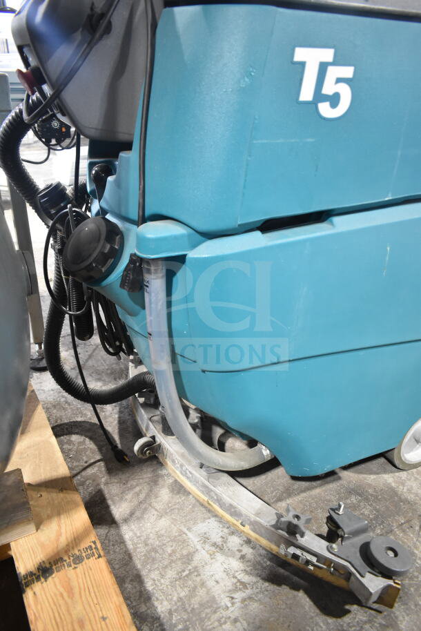 Tennant T5 floor cleaning machine in good condition, featuring hoses and control knobs. Model markings visible.