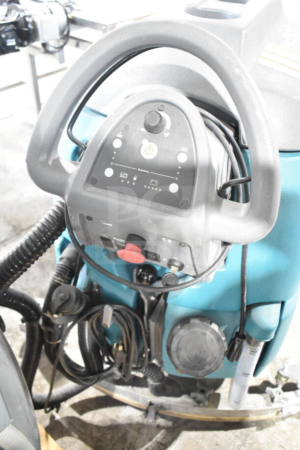 Tennant T5 Floor Cleaning Machine with controls visible. Features ergonomic handle, hoses, and power indicators. Good condition.