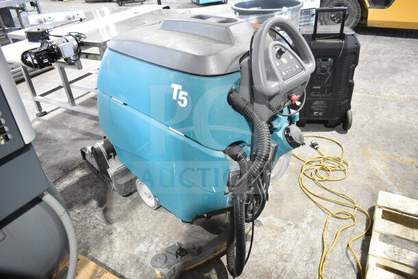 Tennant T5 floor cleaning machine in good condition, featuring control panel, visible hoses, and easily maneuverable wheels.