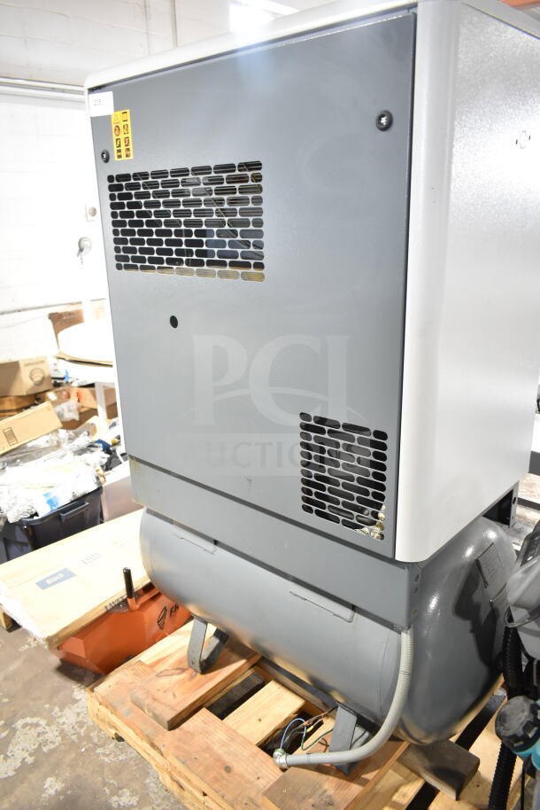 Atlas Copco GA11VSD rotary screw air compressor, gray, used condition, visible safety and model labels, on wooden pallet.