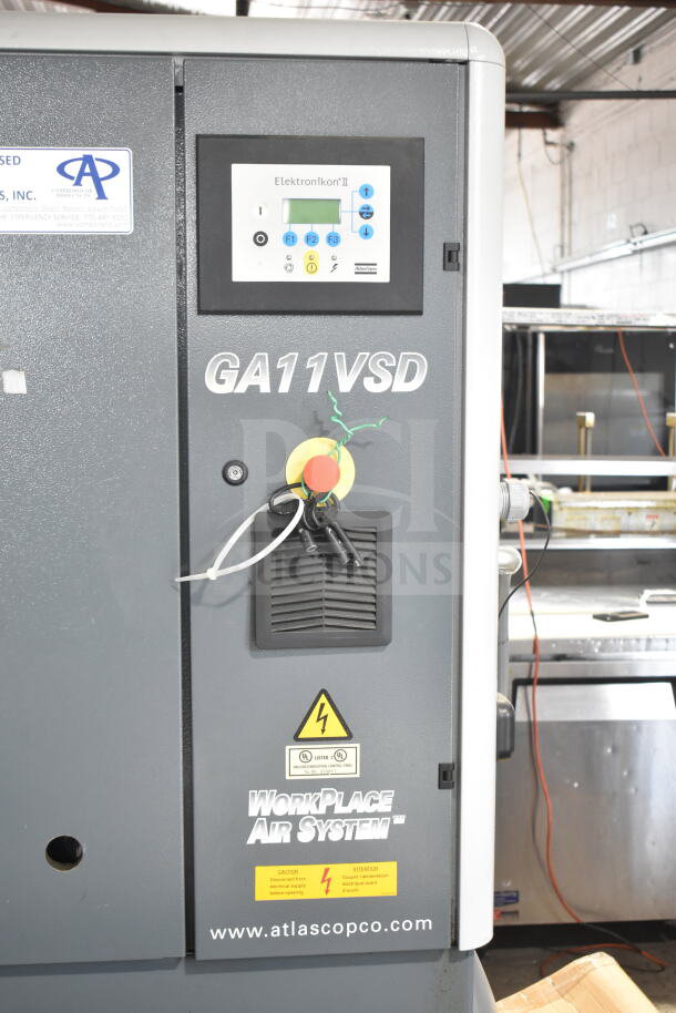 Atlas Copco GA11VSD rotary screw air compressor, Model GA11VSD, control panel, labels indicate electrical warnings.