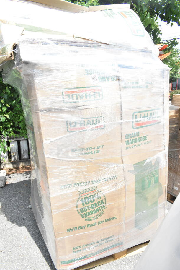 Plastic-wrapped stack of U-Haul boxes on a pallet, labeled "Grand Wardrobe" and "100% Buy Back Guarantee."