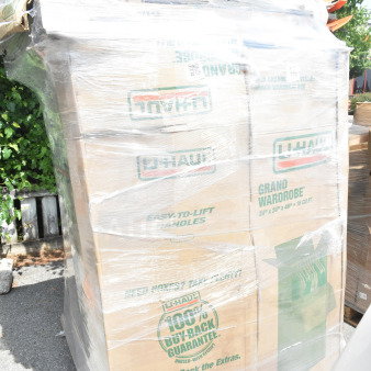 Plastic-wrapped stack of U-Haul boxes on a pallet, labeled "Grand Wardrobe" and "100% Buy Back Guarantee."