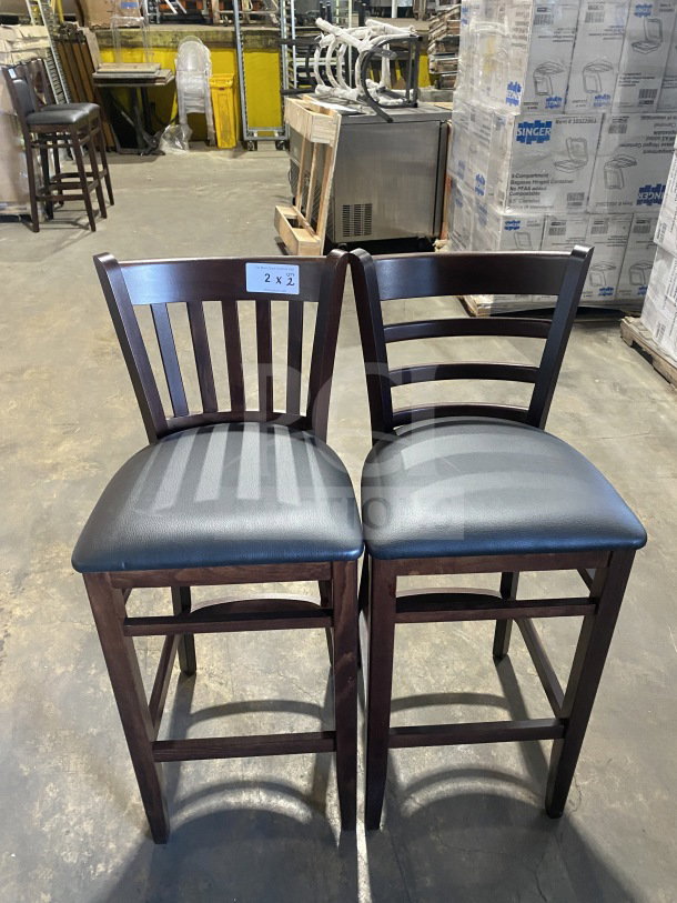 Brand new mahogany finish wood bar stools with black vinyl seats, cushion back design. Auction tag "2X" visible.