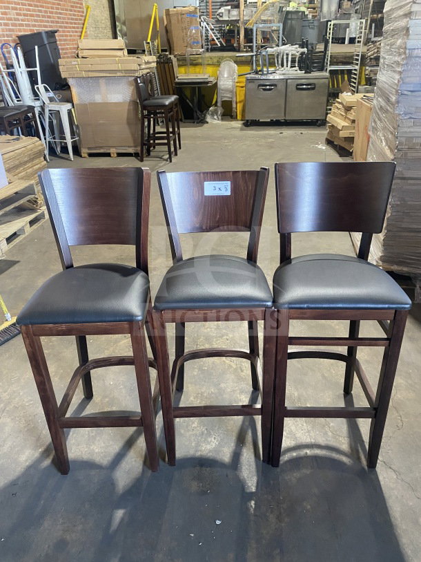 Three brand new mahogany finish wood bar stools with black vinyl seats, cushion back design; labeled "3X" for auction.