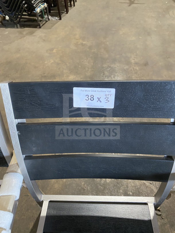 Brand new commercial outdoor teak chair with black slats, metal frame. Auction tag shows "38 X QTY 3" from PCIAuctions.com.