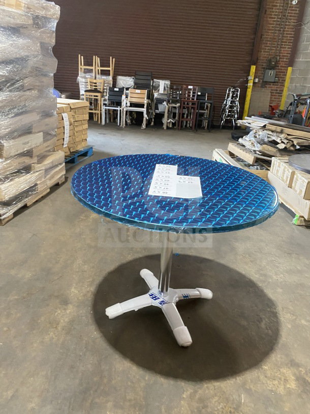 Brand new commercial stainless steel wrapped plate top cocktail table, model D36, with polished base, in warehouse setting.