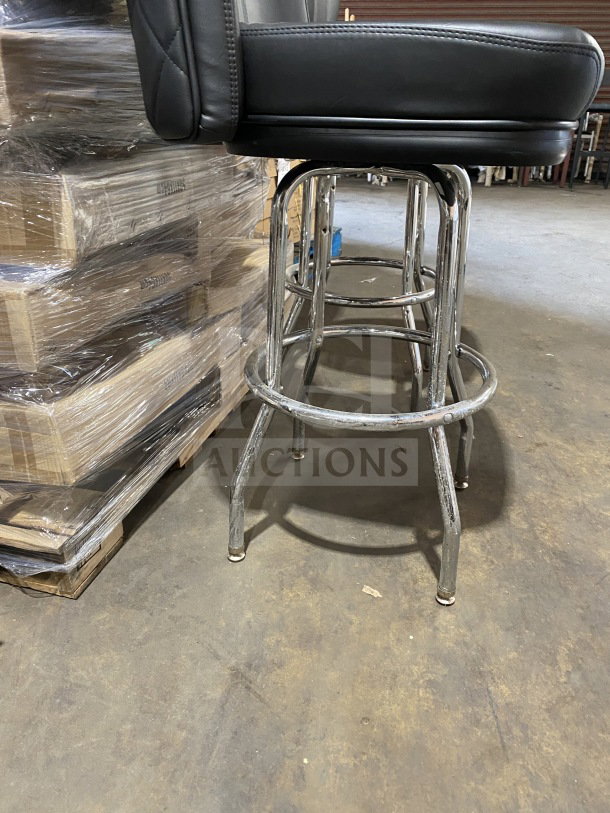 Brand new chrome frame swivel bar stool with black vinyl bucket seat, commercial grade, shown in industrial setting.