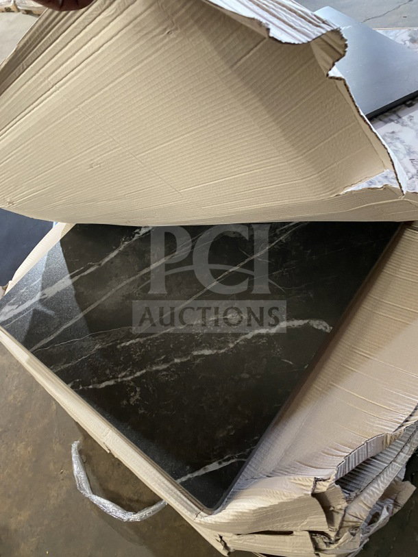 Brand new commercial restaurant table tops, black with white veins, partially boxed, ready for use in cafes or eateries.