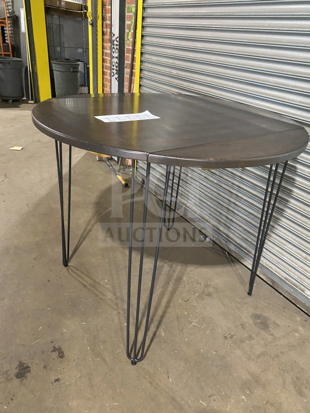 Brand new round 42" composite bar-height table with hairpin legs, suitable for indoor/outdoor use. Auction tag visible.