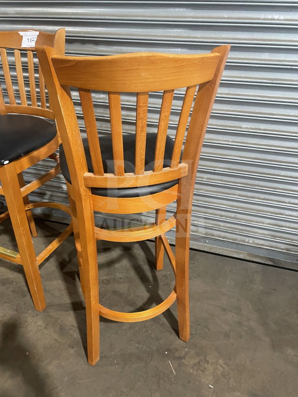 New commercial bar-height stool with vertical slat-back, wooden frame, black vinyl seat. Excellent condition.