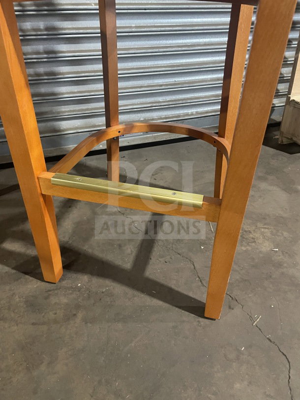 New commercial wooden bar stool with vertical slat-back, black vinyl seat, and footrest. Excellent condition.
