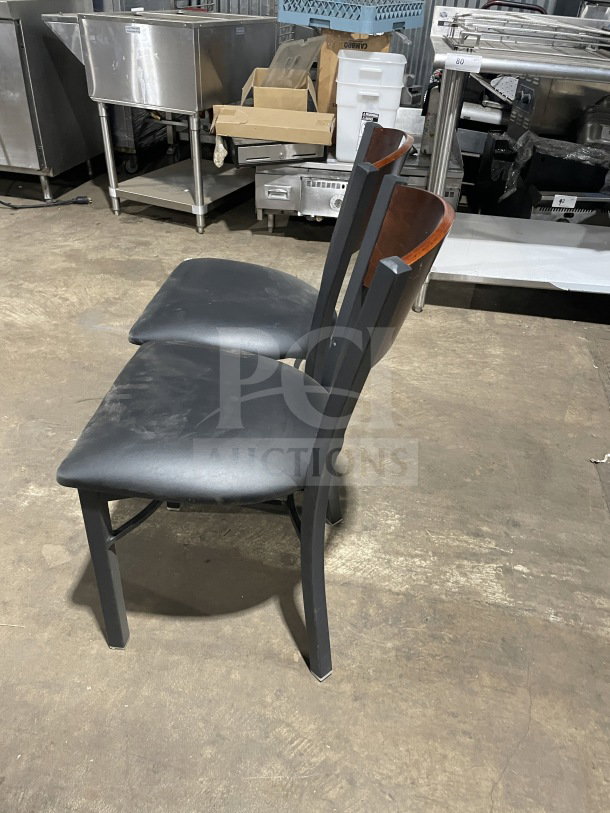 Brand new commercial metal dining chair with cherry wood circle cutout back and black vinyl seat. Auction includes two chairs.