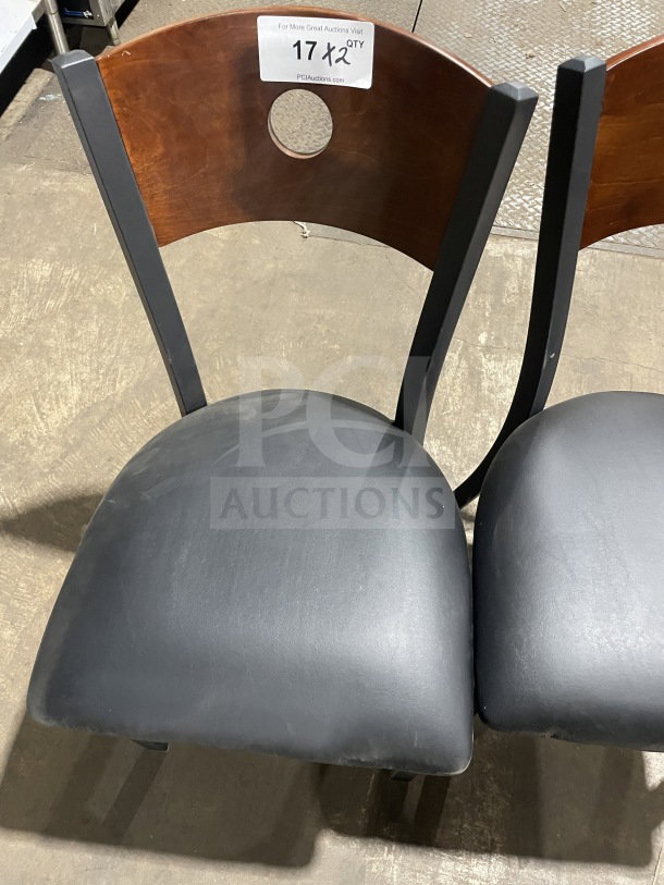 Brand new metal dining chair with cherry wood circle cutout back, black vinyl seat. Commercial use. Auction tag visible.