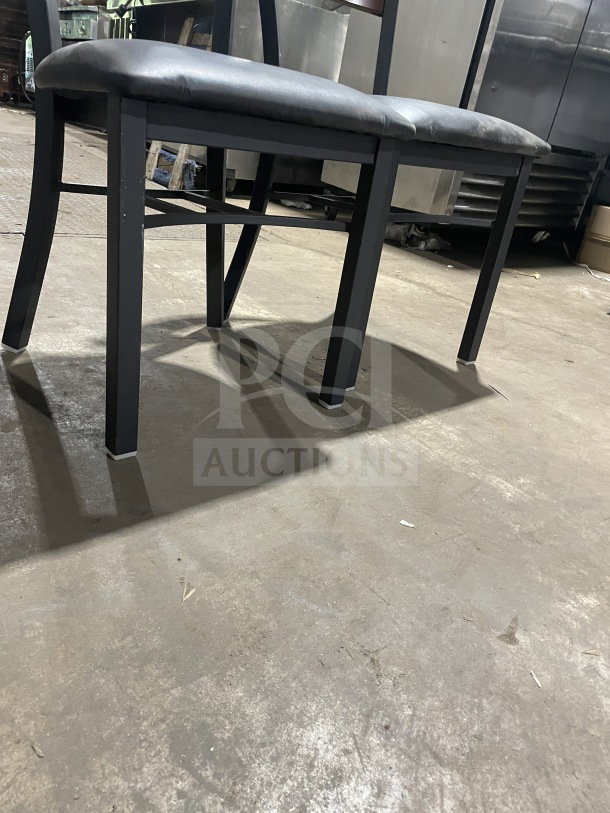 Brand new commercial metal dining chair with cherry wood circle cutout back and black vinyl seat, in excellent condition.