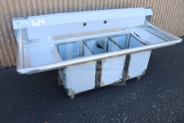Brand new Steelton 522CS31014LR 54" commercial sink, three compartments, two 12" drainboards, slight dents visible.