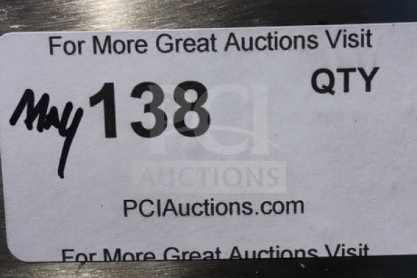 Sticker on a stainless steel water station indicating auction information, labeled "138" with website PCIauctions.com.