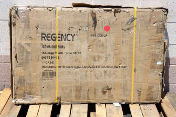 BRAND NEW Regency 600TS3048S 30" x 48" stainless steel work table in damaged original packaging; model and specs visible.