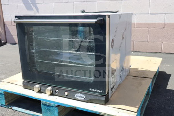 Brand new Cadco Arianna XAF-133 4-shelf convection oven on a pallet, manual controls, stainless steel, 208-240V.