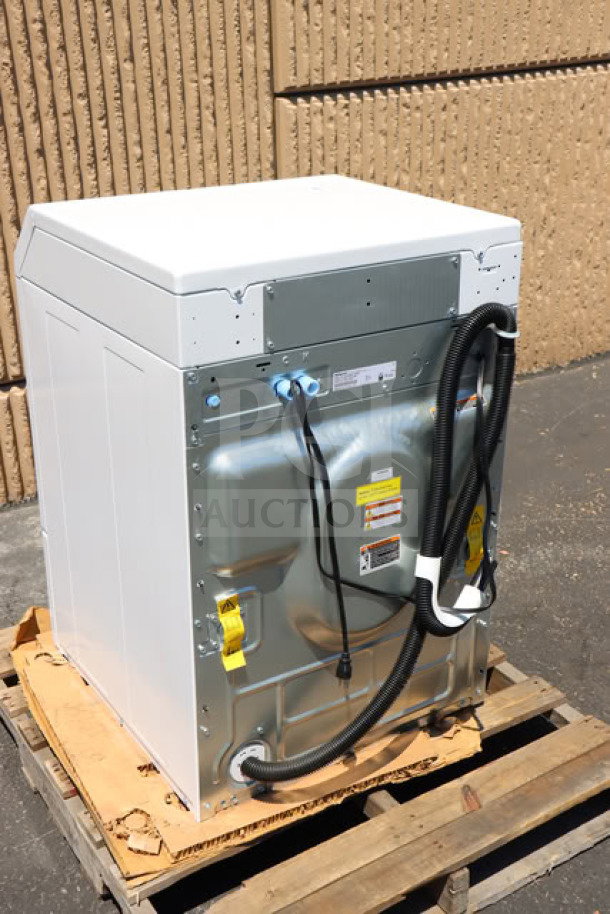 Brand new Speed Queen FF7012WN 3.5 cu. ft. front load washer, back view, showing hoses and fittings on a wooden pallet.