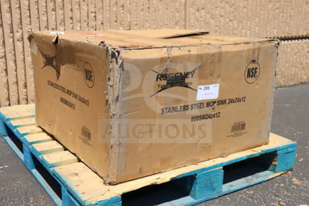 Damaged box containing Regency 600SM242412 stainless steel mop sink, 24"x24"x12" bowl, on pallet. Box shows product details.