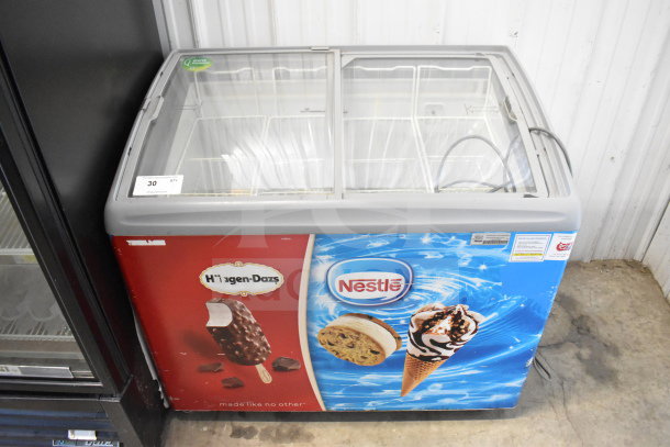 AHT RIO S 100 commercial chest freezer merchandiser with glass lid, featuring Haagen-Dazs and Nestle branding. 115 Volts, good condition.