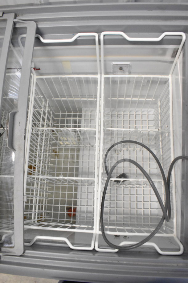 AHT RIO S 100 commercial chest freezer merchandiser, 115 volts, 1 phase, open lid view with metal baskets, power cord visible.