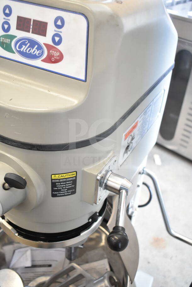 2025 Globe SP30 commercial dough mixer with bowl, guard, and attachments. Features start/stop buttons and safety caution label.