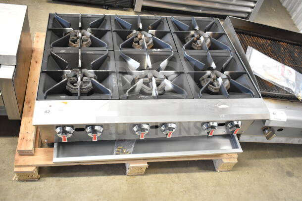 Commercial countertop gas-powered 6-burner range with stainless steel finish, visible control knobs, and burner grates.