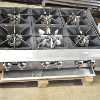 Commercial countertop gas-powered 6-burner range with stainless steel finish, visible control knobs, and burner grates.