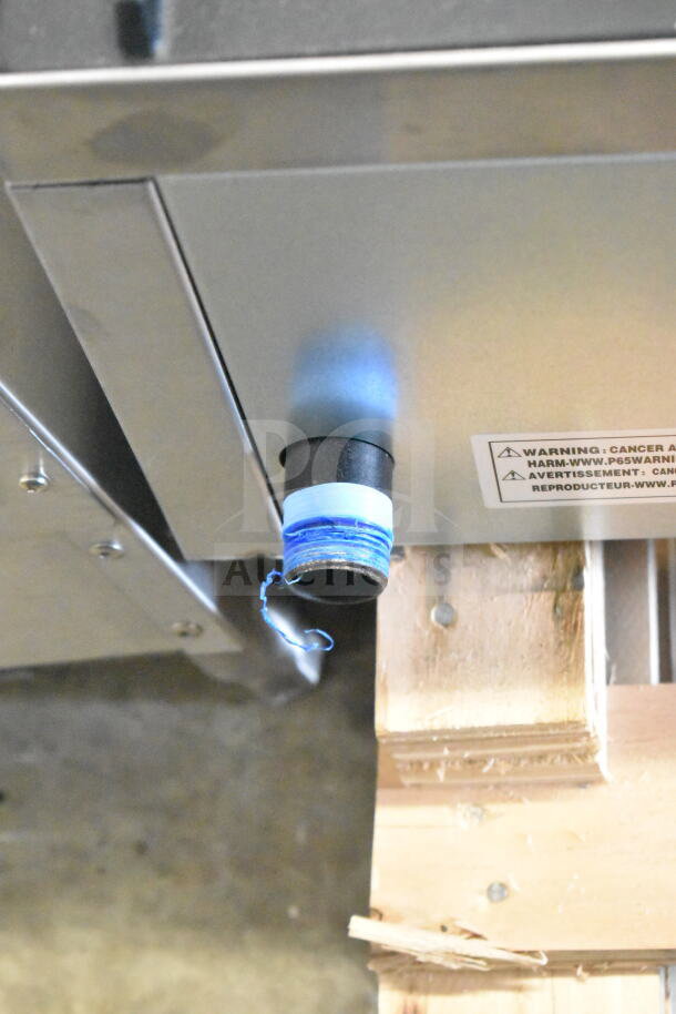 Commercial countertop gas-powered 6 burner range, close-up of gas connection with blue tape, visible warning label.