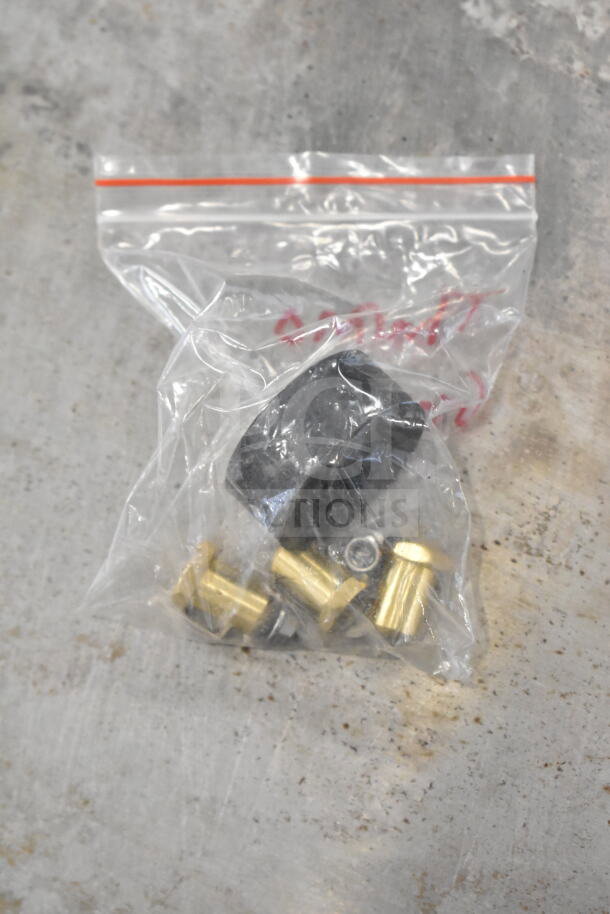Small plastic bag containing a black knob and brass fittings on a concrete surface.