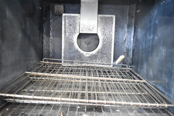 Imperial commercial convection oven interior with metal racks, showing visible wear. Features thermostatic controls.