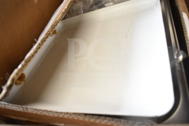 Box containing a variety of fry pans and utensils. Visible is a white, rectangular enamel tray. Condition appears used.