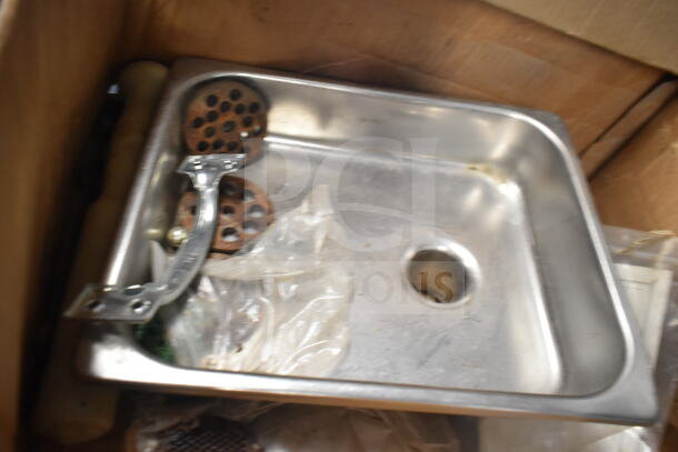 Metal meat grinder attachment with tray, includes perforated discs, appears used, metallic finish.