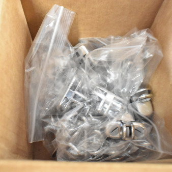 Box of various metal pieces in plastic bags. Items appear new, organized for auction sale.