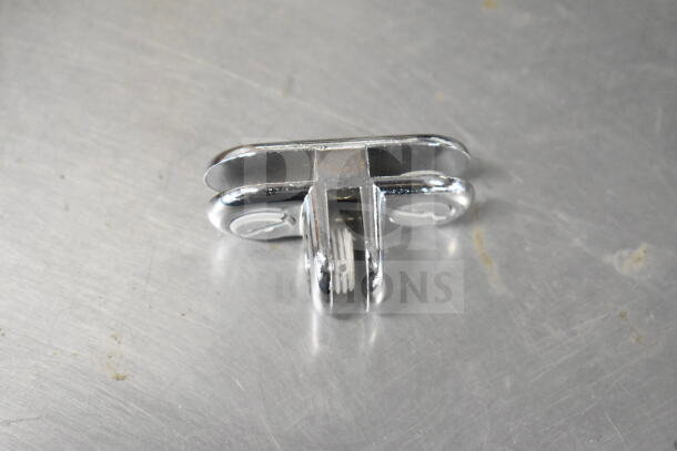 Chrome metal clip with grooved center, suitable for mechanical fastening. In good condition, reflective surface.