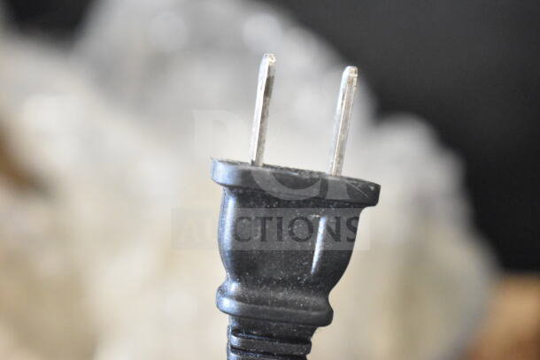 Close-up of a two-prong electrical plug for the Jura 118 Espresso Machine. 120 Volts, 1 Phase. Black plastic housing.