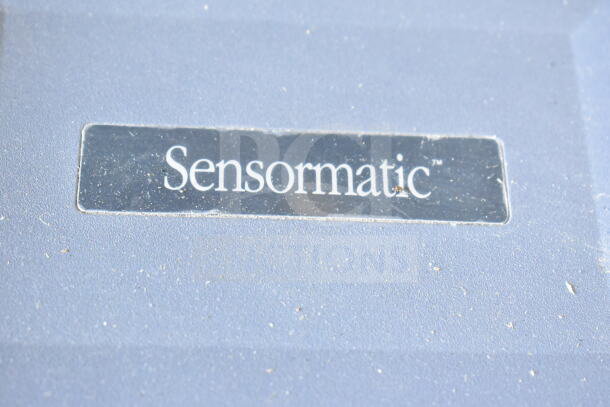 Sensormatic label on a device, possibly part of the auctioned Sensormatic items set, condition appears used.