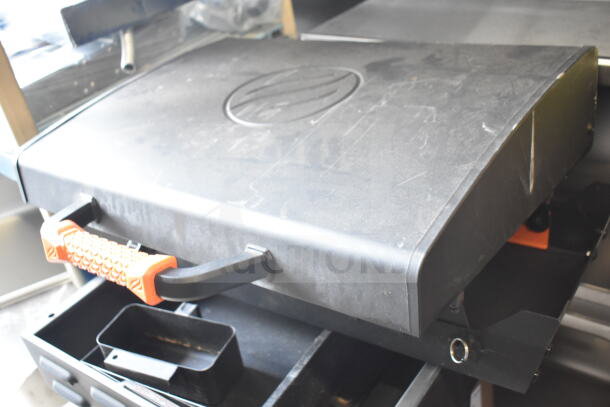 Flat top griddle for grill with orange handle, showing some wear. Ideal for outdoor cooking.