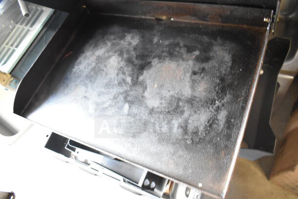 Flat top griddle for grill, used condition, darkened and seasoned surface, designed for outdoor cooking.