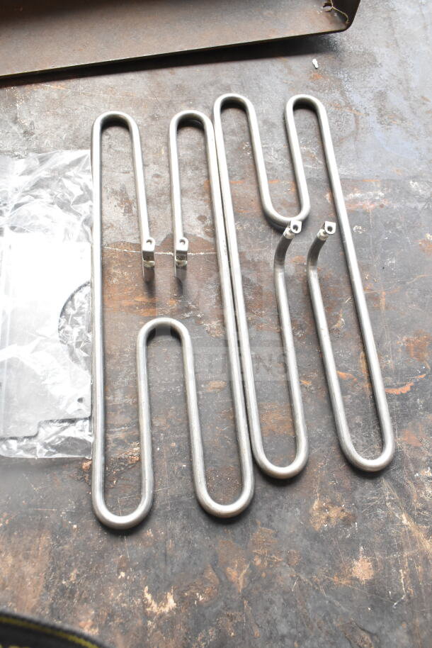 Four new metal burners and pieces, scratched and dented, on a table. Auction lot includes four items, enhancing bid value.