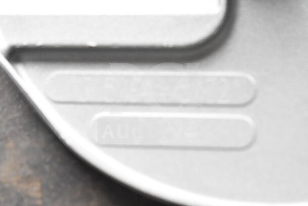 Close-up of metallic item surface with engraved markings. Part of a lot including Robot Coupe blade and MainStreet Equipment oven knob.
