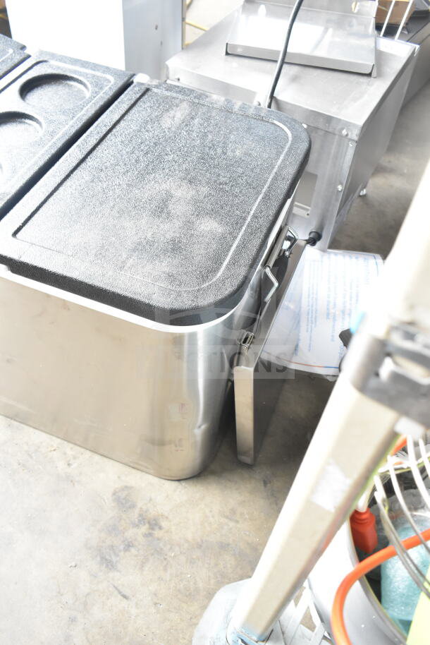 Brand new cooler with minor dents, stainless steel body, black textured lid, dual compartments, latch closures.