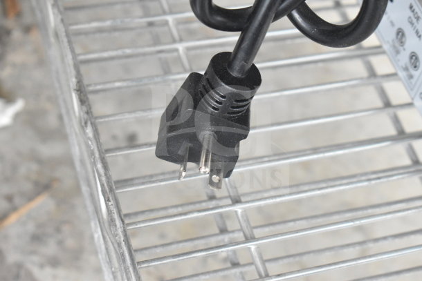 Black power cord plug for Avantco 177F202 fryer, resting on a metal wire shelf.